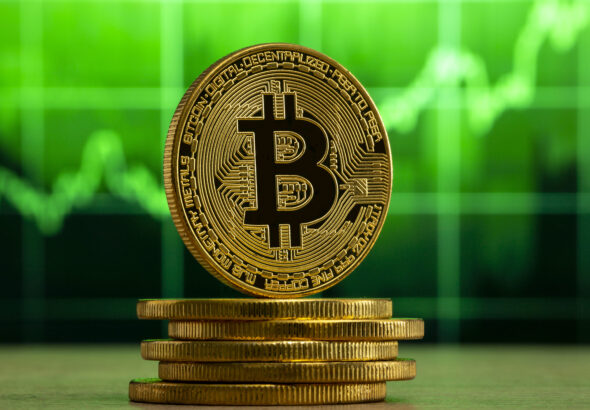 physical-bitcoin-standing-wood-table-front-green-graph-bitcoin-bull-market-concept